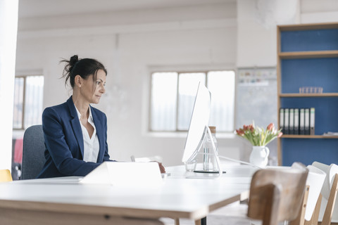 Geschäftsfrau arbeitet am Schreibtisch in einem Loft, lizenzfreies Stockfoto