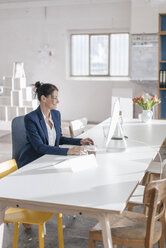 Businesswoman working at desk in a loft - JOSF01159