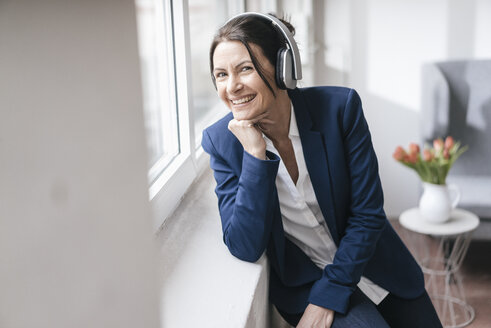 Porträt einer Frau, die mit Kopfhörern Musik hört - JOSF01179
