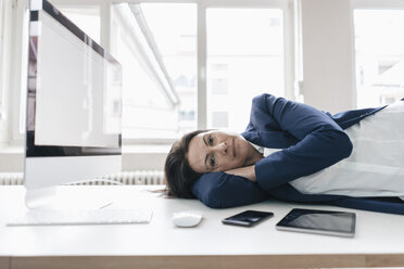 Geschäftsfrau entspannt sich auf dem Schreibtisch im Büro - JOSF01196
