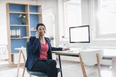 Portrait of businesswoman sitting at desk in a loft - JOSF01202