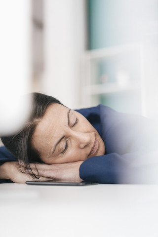 Überarbeitete Frau schläft am Laptop im Büro, lizenzfreies Stockfoto