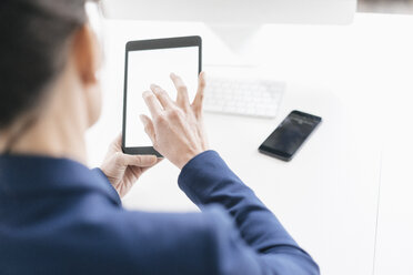 Rückenansicht einer Geschäftsfrau, die ein Tablet im Büro benutzt - JOSF01214