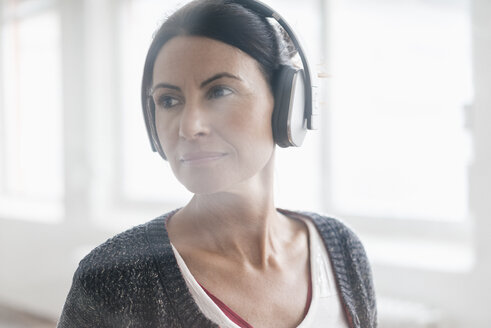 Porträt einer Frau, die mit Kopfhörern Musik hört - JOSF01217