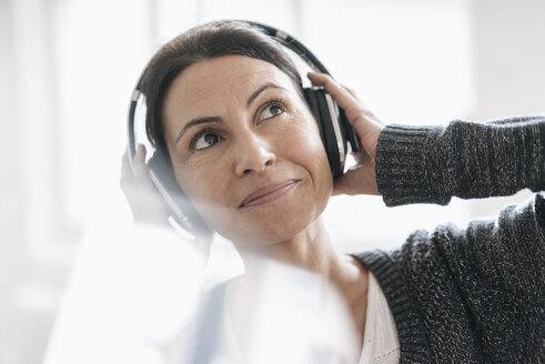 Porträt einer lächelnden Frau, die mit Kopfhörern Musik hört - JOSF01218