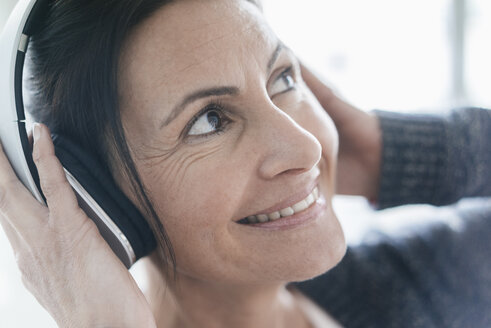 Porträt einer lächelnden Frau, die mit Kopfhörern Musik hört - JOSF01219