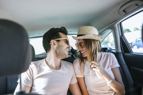 Lachendes Ehepaar auf dem Rücksitz eines Autos - KIJF01589