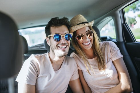 Lachendes Ehepaar auf dem Rücksitz eines Autos - KIJF01590