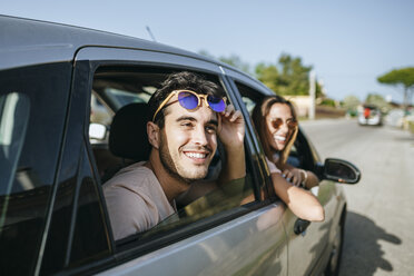 Happy young man and woman in a car looking out the window - KIJF01594