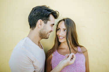 Junges Paar, das sich verliebt vor einer gelben Wand ansieht - KIJF01600
