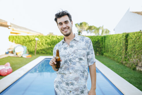 Young man drinking beer at the poolside - KIJF01613