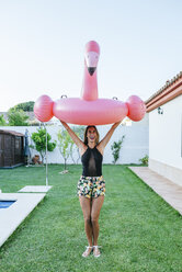 Woman holding pink flamingo float at the poolside - KIJF01628