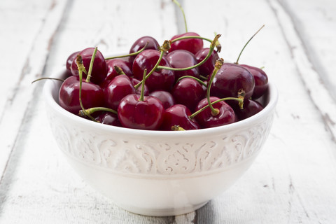 Bowl of cherries on white wood stock photo