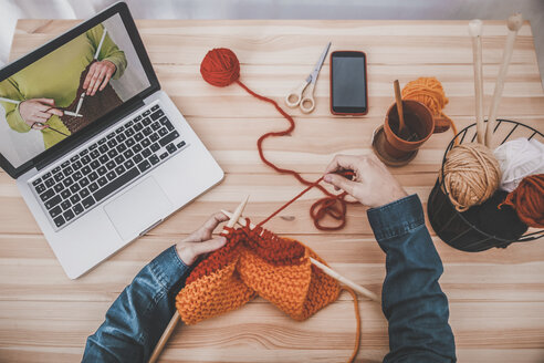 Knitting man using laptop for watching online tutorial, partial view - RTBF00905