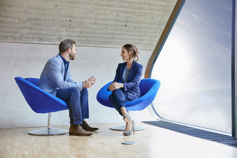 Man and woman sitting on chairs talking stock photo