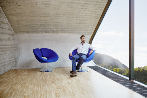 Geschäftsmann sitzt auf einem Stuhl in einem Dachbodenbüro - RHF01931