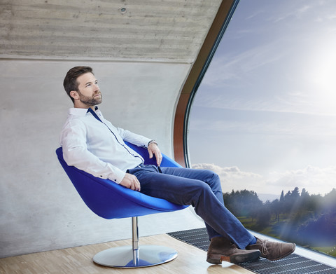 Businessman sitting on chair in attic office stock photo