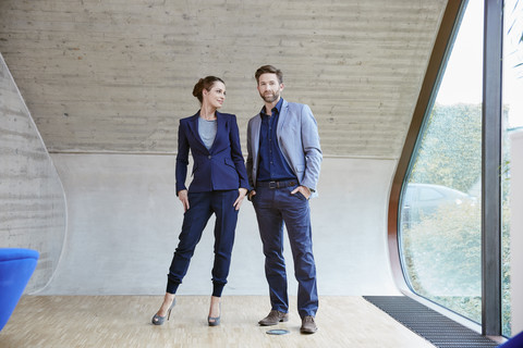 Portrait of man and woman standing in attic office stock photo