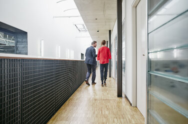 Businessman and businesswoman walking on office floor - RHF01972