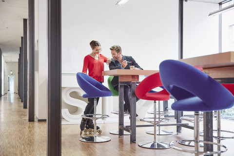 Man and woman with inline skates having lunch break in office stock photo