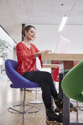 Woman with inline skates using laptop in office - RHF01982