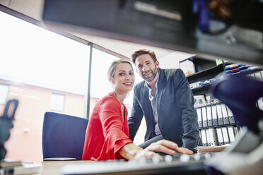 Smiling man and woman at desk in office - RHF01986