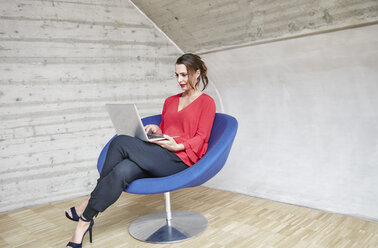 Geschäftsfrau sitzt auf einem Stuhl und benutzt einen Laptop - RHF01993