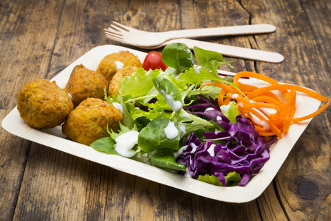 Falafel and salad on wooden disposable plates and cutlery stock photo