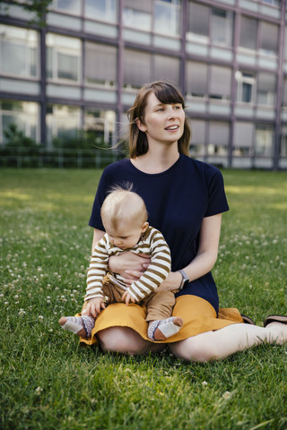 Mother sitting with her baby boy on a meadow stock photo