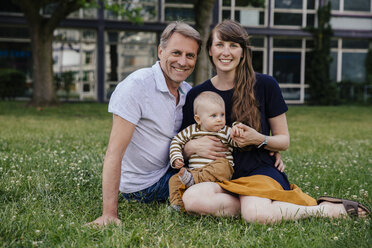 Happy parents sitting on a meadow with little son - MFF03652