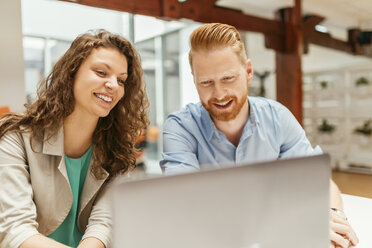 Businessman and woman using laptop in office - ZEDF00593