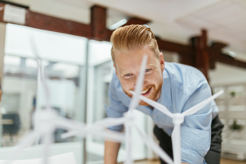 Geschäftsmann im Büro mit Blick auf Modelle von Windkraftanlagen, lizenzfreies Stockfoto