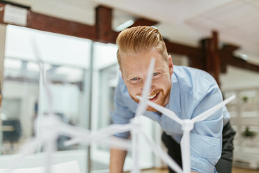 Geschäftsmann im Büro mit Blick auf Modelle von Windkraftanlagen - ZEDF00602