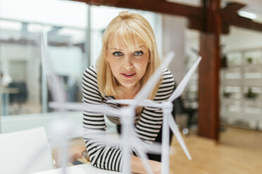 Businesswoman in office looking at models of wind turbines - ZEDF00604