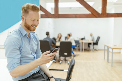 Geschäftsmann in Bürobesprechung mit Smartphone - ZEDF00640