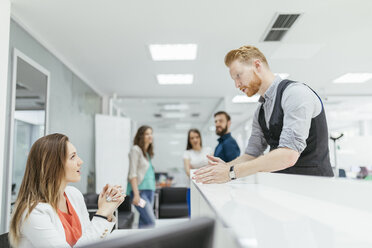 Businessman and woman discussing in office, colleagues watching - ZEDF00642