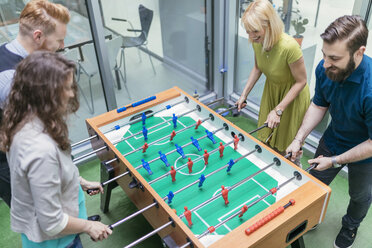 Colleagues playing foosball in office - ZEDF00648