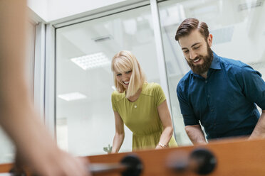 Colleagues playing foosball in office - ZEDF00650