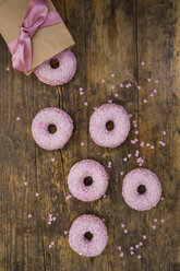 Krapfen mit rosa Zuckerguss und Zuckergranulat und Backdekor auf Holz - LVF06171
