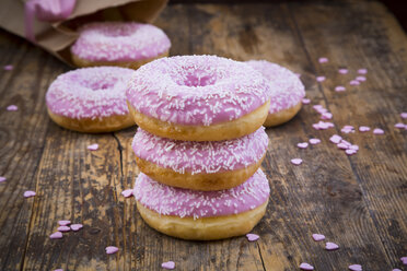 Krapfenstapel mit rosa Zuckerguss und Zuckerkörnern auf Holz - LVF06173