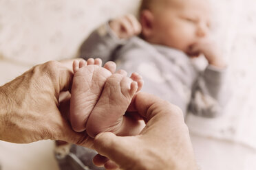 Feet of newborn baby boy being held by father’s hands - MFF03658