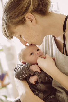 Mutter testet den Hunger des Neugeborenen mit ihrem Finger und küsst seine Stirn - MFF03669