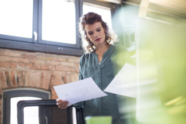 Junge Frau arbeitet am Schreibtisch in einem modernen Büro - FKF02386