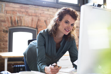 Junge Frau arbeitet am Schreibtisch in einem modernen Büro - FKF02387