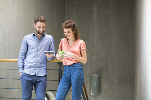 Mann und Frau im Treppenhaus mit Handy und Tasse Kaffee - FKF02407