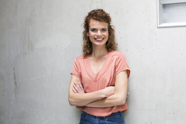 Portrait of smiling woman leaning against concrete wall - FKF02421