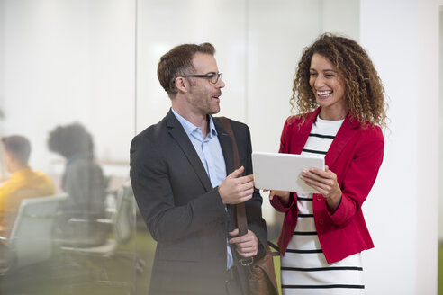 Businessman and businesswoman with tablet talking in office - ZEF13996