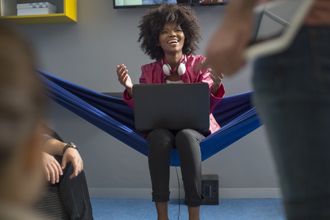 Happy woman in hammock with laptop stock photo