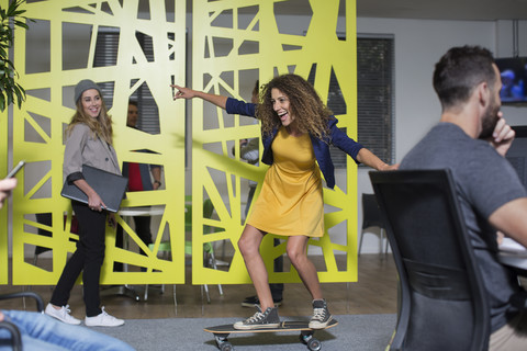 Frau auf Skateboard im Büro hat Spaß, lizenzfreies Stockfoto