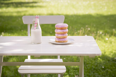 Stapel von Donuts und Milchflasche auf dem Gartentisch - LVF06193